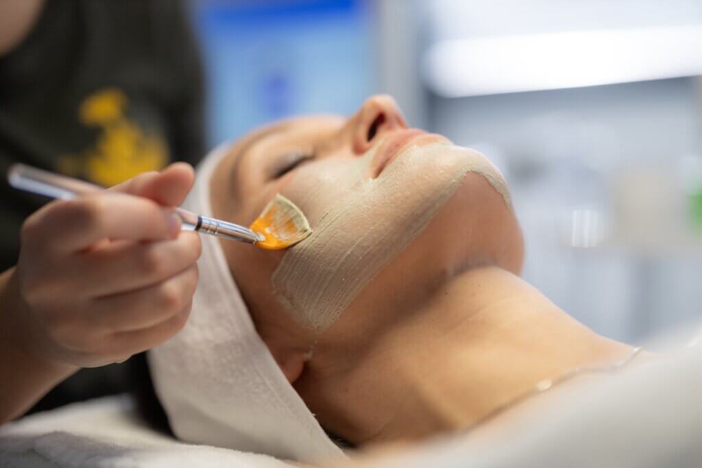 Professionelle Gesichtsbehandlung mit natürlicher Pflege im Spa – eine Person entspannt sich bei der sanften Anwendung einer Gesichtsmaske.